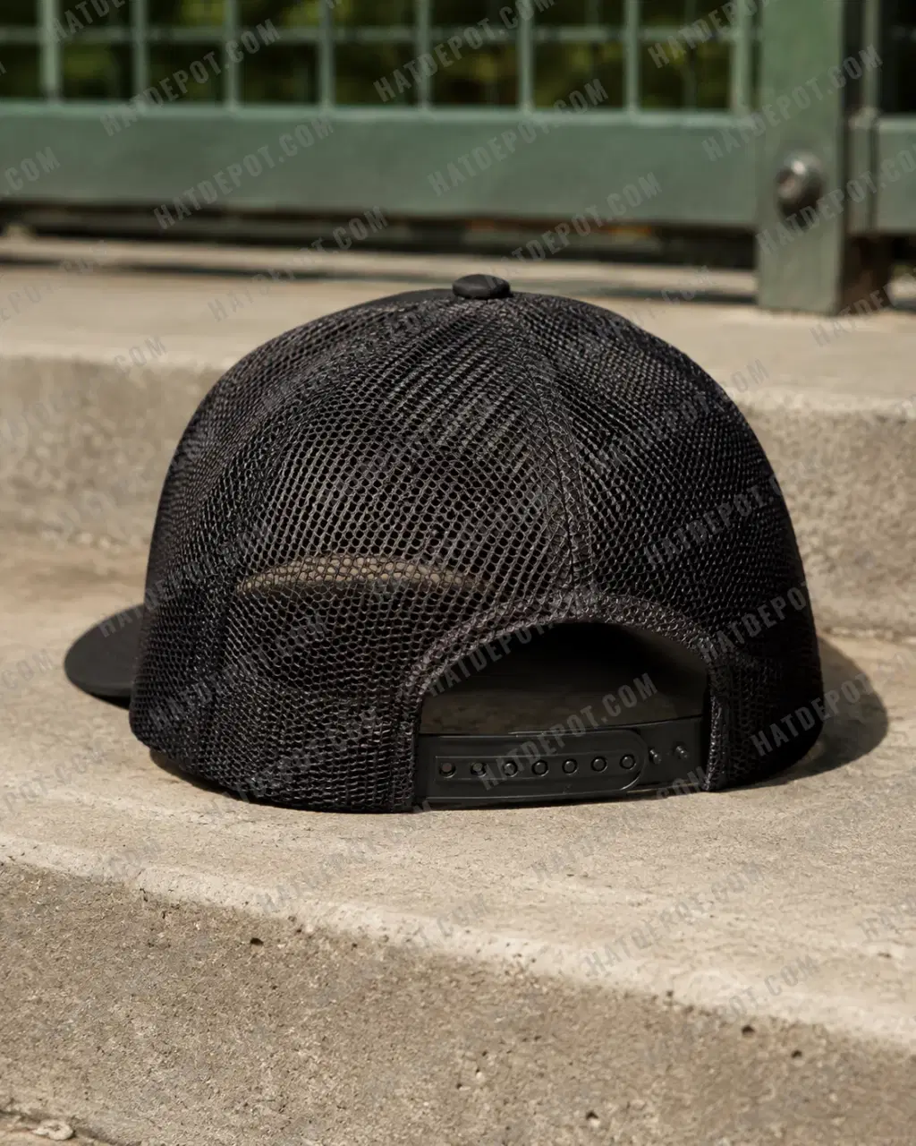 Rear detail of the black Curved Brim Trucker Snapback, showing the open mesh, center seam and adjustable plastic snap closure.