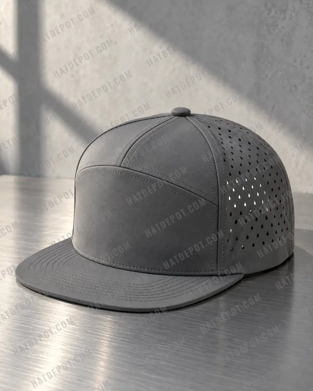 Charcoal Seven-Panel Perforated Snapback on brushed steel, with directional light showing its flat brim, seamless front, two solid crown panels and laser-cut vents.