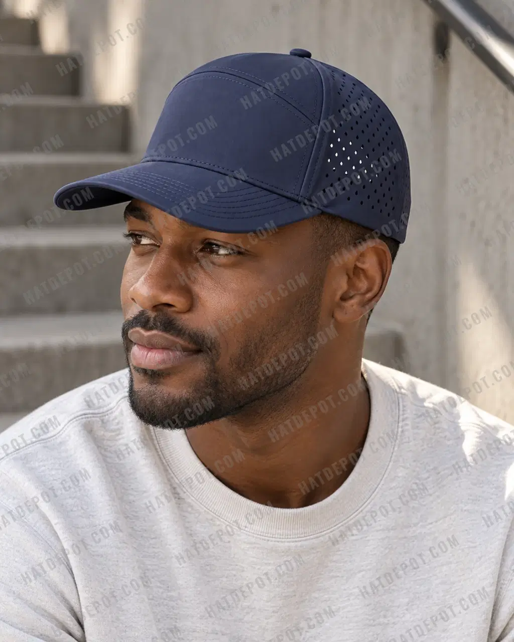 Daylight three-quarter profile of a model wearing the navy Six-Panel Perforated Snapback, with its curved brim, seamless front and laser-cut side vents visible.